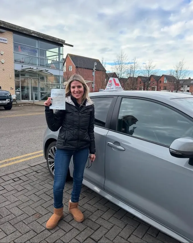 Arin with their pass certificate beside a Learn Local car