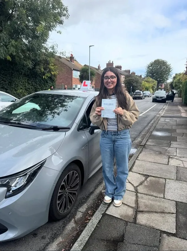 A Learn Local learner with their pass certificate beside the car